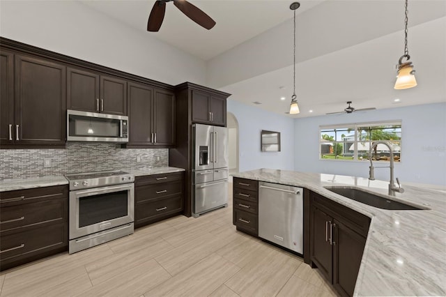 kitchen featuring sink, appliances with stainless steel finishes, backsplash, dark brown cabinetry, and decorative light fixtures