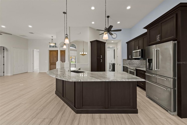 kitchen featuring sink, hanging light fixtures, a large island with sink, and appliances with stainless steel finishes