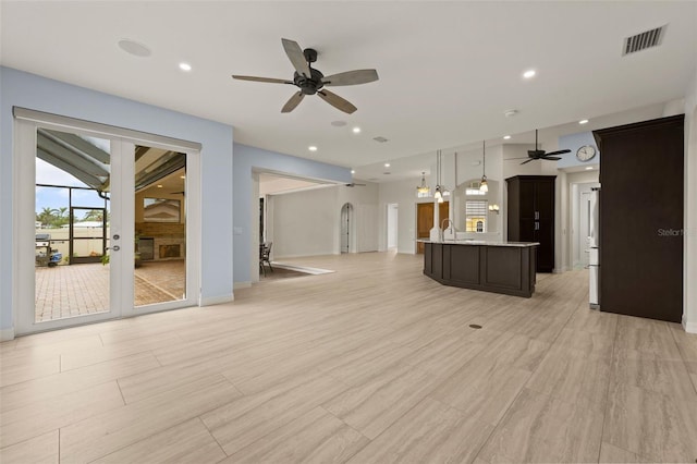 unfurnished living room featuring ceiling fan and sink