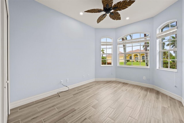 empty room featuring ceiling fan, plenty of natural light, and light wood-type flooring