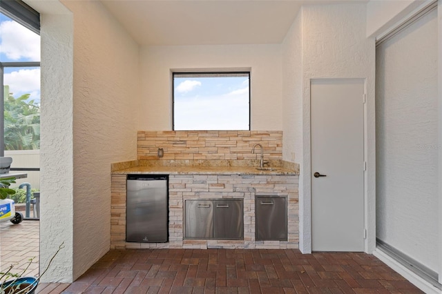 bar featuring sink and stainless steel fridge