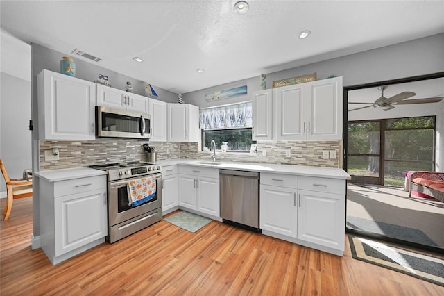 kitchen with stainless steel appliances, sink, white cabinets, and decorative backsplash