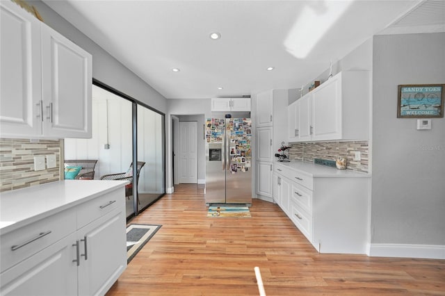 kitchen with stainless steel refrigerator with ice dispenser, white cabinetry, decorative backsplash, and light hardwood / wood-style flooring