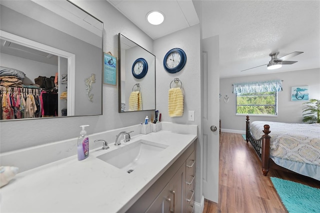 bathroom with vanity, wood-type flooring, ceiling fan, and a textured ceiling