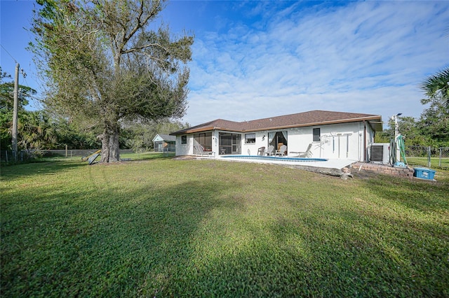 rear view of house with a fenced in pool, a lawn, a sunroom, and a patio