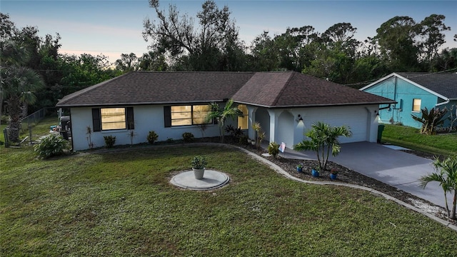 ranch-style home featuring a garage and a lawn