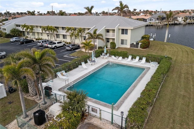 view of pool with a patio, a water view, central AC unit, and a lawn