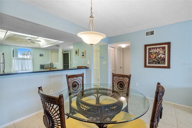 dining space with sink, light tile patterned floors, ceiling fan, and a tray ceiling