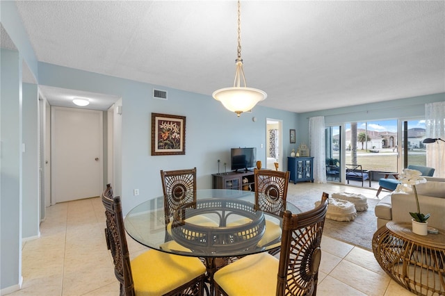 dining space featuring light tile patterned flooring and a textured ceiling