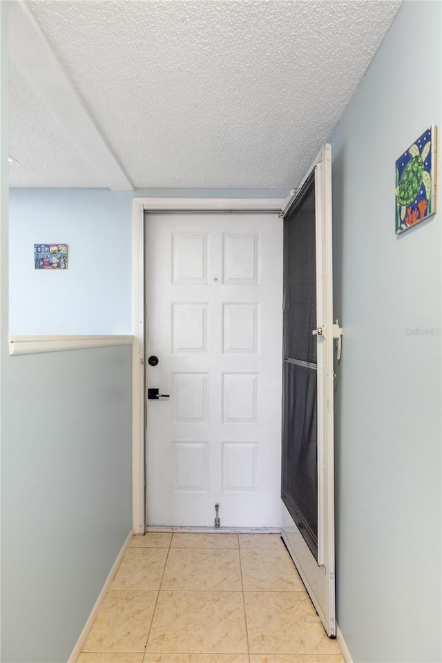 doorway to outside with a textured ceiling and light tile patterned floors