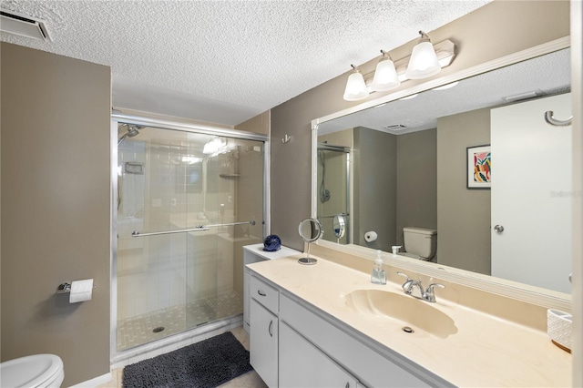 bathroom with a textured ceiling, a shower with door, toilet, and vanity