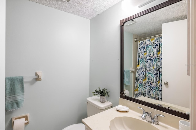 bathroom featuring toilet, a textured ceiling, and vanity