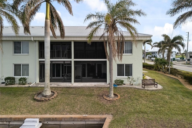 back of property featuring a sunroom and a lawn