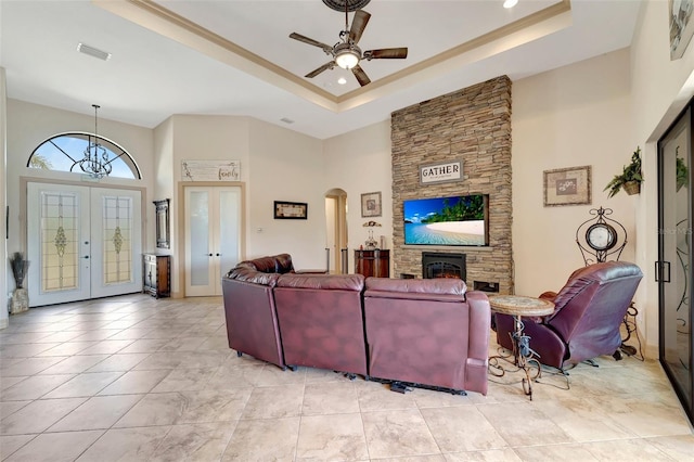 tiled living room featuring french doors, a towering ceiling, a fireplace, and a raised ceiling