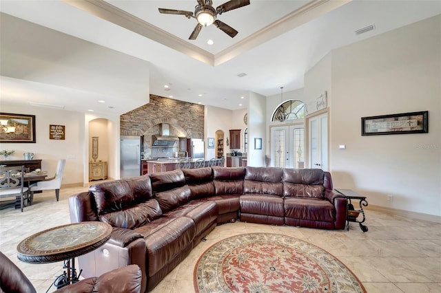 living room featuring ceiling fan, ornamental molding, french doors, and a raised ceiling