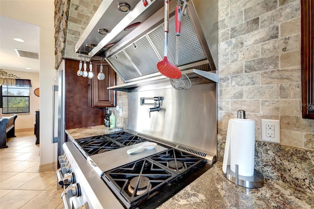 kitchen featuring light stone counters, backsplash, and high end stainless steel range