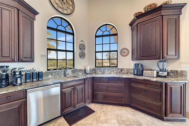 kitchen featuring sink, light tile patterned floors, dishwasher, a towering ceiling, and light stone countertops