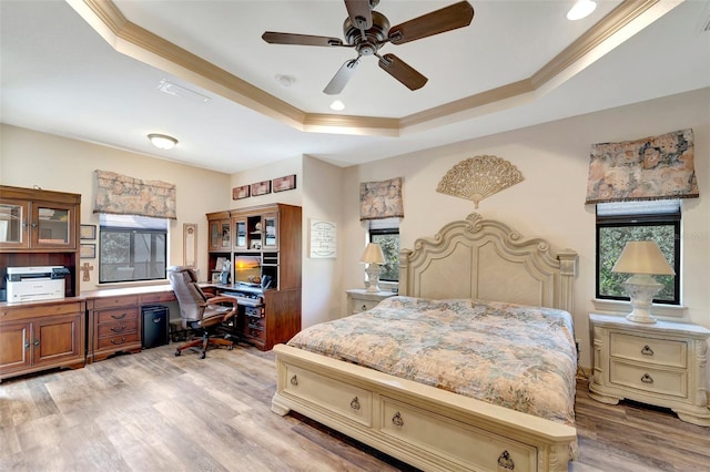 bedroom featuring a raised ceiling, ornamental molding, ceiling fan, and light hardwood / wood-style flooring