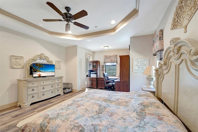 bedroom with ceiling fan, ornamental molding, a raised ceiling, and light wood-type flooring