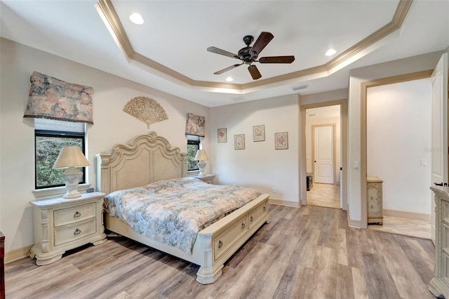 bedroom with light wood-type flooring, ceiling fan, and a tray ceiling