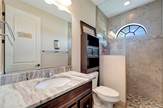 bathroom featuring vanity, toilet, and a tile shower