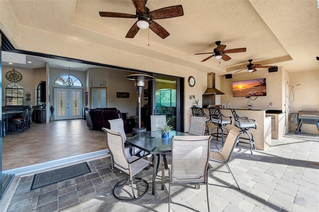 dining space with a raised ceiling, a textured ceiling, and french doors