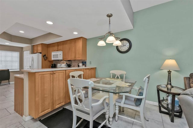 kitchen featuring decorative light fixtures, tasteful backsplash, light tile patterned floors, kitchen peninsula, and white appliances