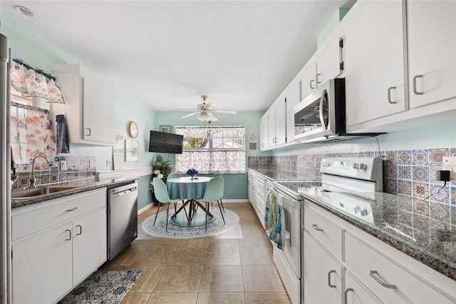 kitchen featuring appliances with stainless steel finishes, tasteful backsplash, white cabinetry, sink, and dark stone countertops