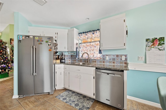 kitchen featuring sink, white cabinetry, stainless steel appliances, light tile patterned flooring, and dark stone counters