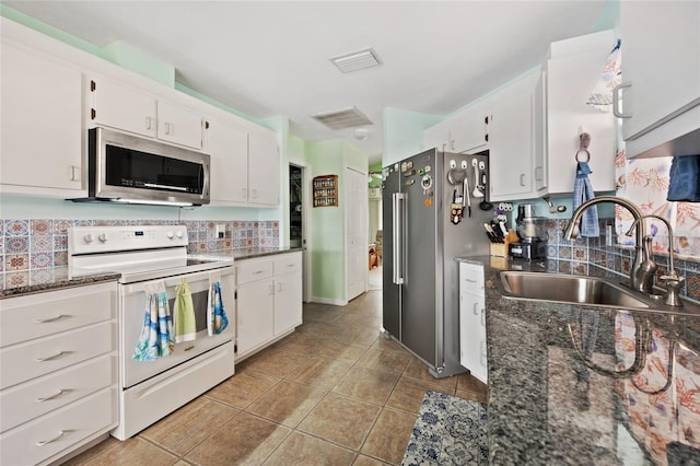 kitchen featuring stainless steel appliances, sink, dark stone countertops, and white cabinets