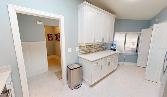 kitchen with white cabinetry, backsplash, and light tile patterned flooring