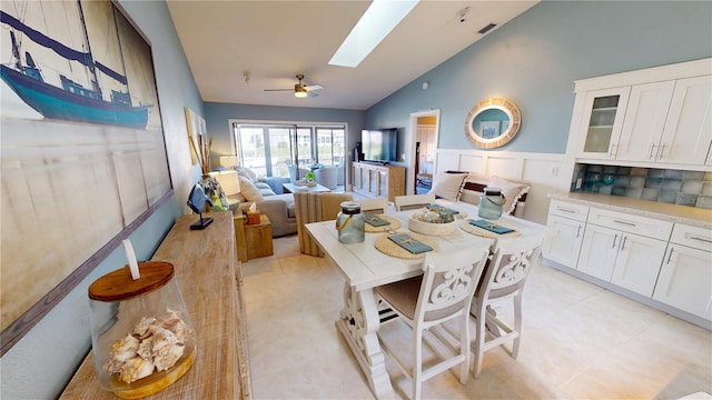 dining room with ceiling fan and vaulted ceiling with skylight