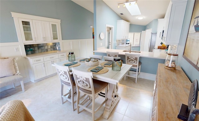 dining area with light tile patterned flooring and vaulted ceiling with skylight