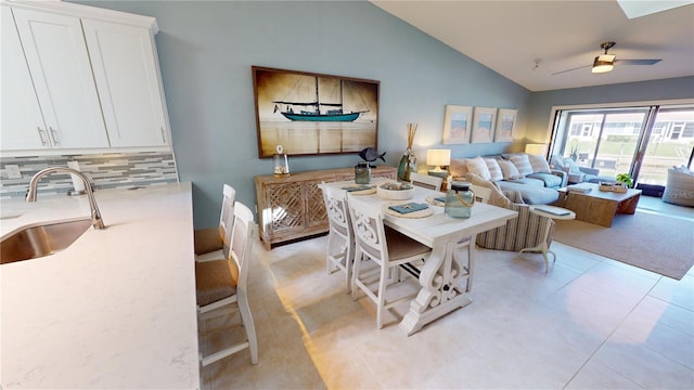 tiled dining area featuring vaulted ceiling, ceiling fan, and sink