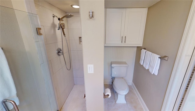 bathroom with tile patterned flooring, a tile shower, and toilet