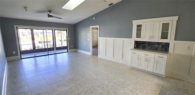 unfurnished living room with light tile patterned floors, lofted ceiling with skylight, and ceiling fan