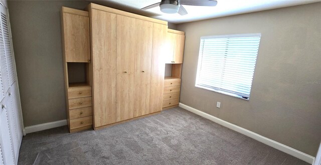 unfurnished bedroom with dark colored carpet and ceiling fan