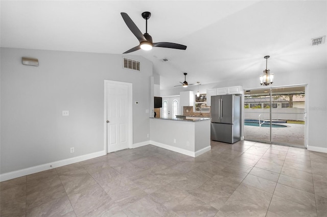 unfurnished living room featuring ceiling fan with notable chandelier, lofted ceiling, and a wealth of natural light