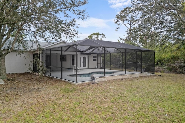 rear view of property with a yard, a patio area, and glass enclosure