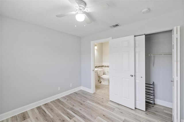 unfurnished bedroom featuring ensuite bath, light hardwood / wood-style flooring, ceiling fan, and a closet