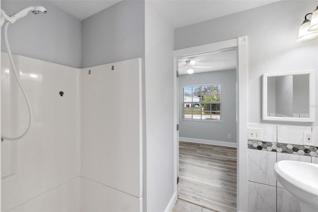 bathroom with walk in shower, ceiling fan, sink, and tile walls