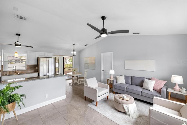 living area featuring lofted ceiling, visible vents, and ceiling fan with notable chandelier