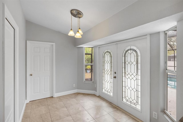 entrance foyer with french doors, light tile patterned floors, an inviting chandelier, vaulted ceiling, and baseboards