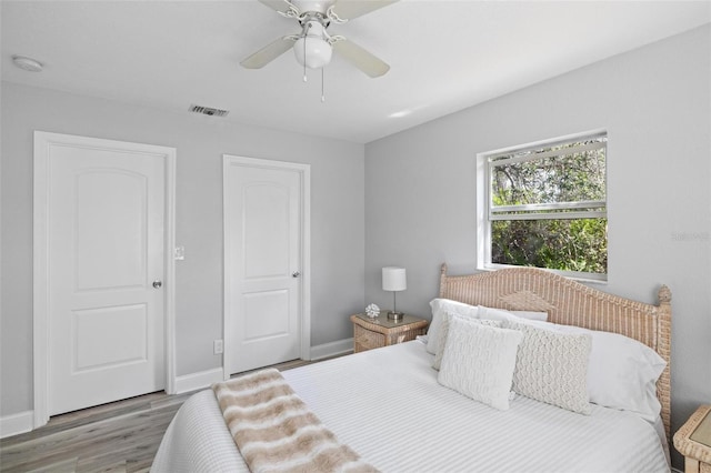 bedroom featuring ceiling fan, wood finished floors, visible vents, and baseboards