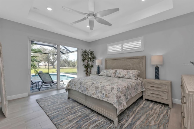 bedroom with access to outside, a raised ceiling, a sunroom, and baseboards