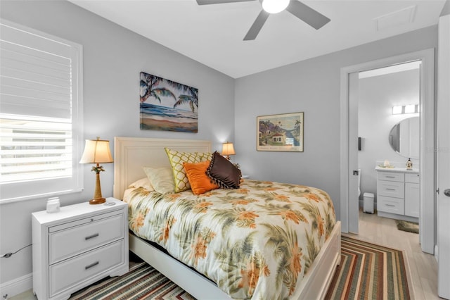 bedroom with ceiling fan, wood finished floors, and connected bathroom