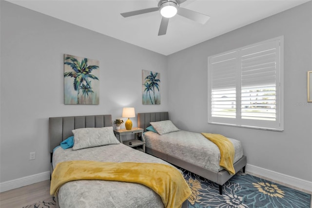 bedroom with ceiling fan, wood finished floors, and baseboards