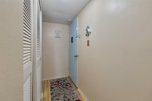 hallway with hardwood / wood-style floors and a textured ceiling