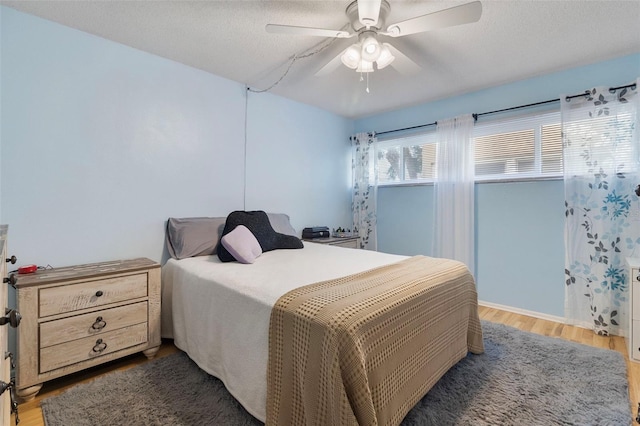 bedroom with hardwood / wood-style flooring, a textured ceiling, and ceiling fan