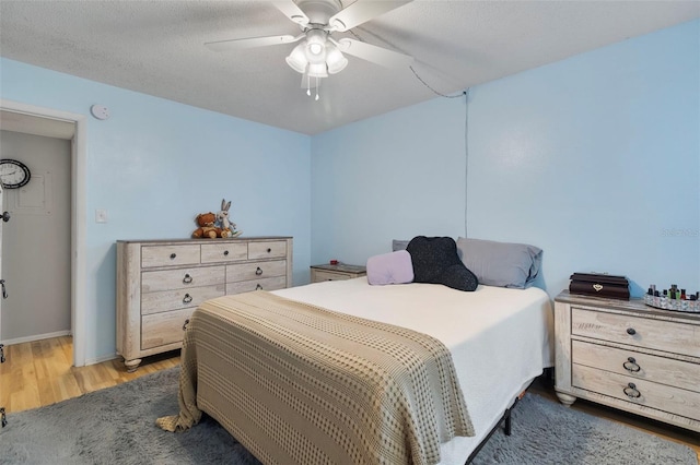 bedroom with dark wood-type flooring, a textured ceiling, and ceiling fan